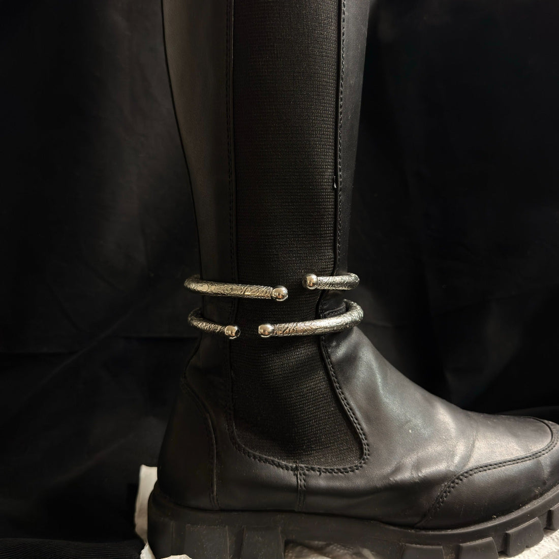 Two engraved oxidized brass boot cuffs worn on black boot