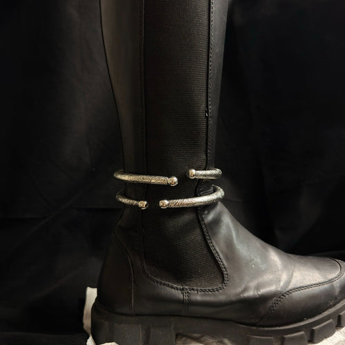 Two engraved oxidized brass boot cuffs worn on black boot